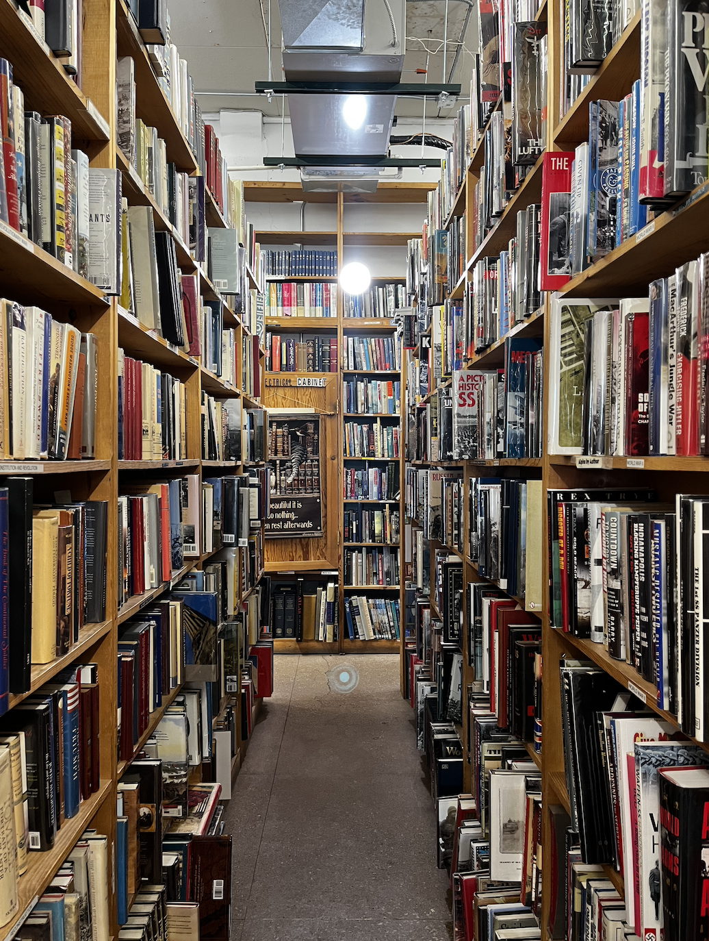 Interior of Midway Books, towering shelves full of books loom on either side and at the end